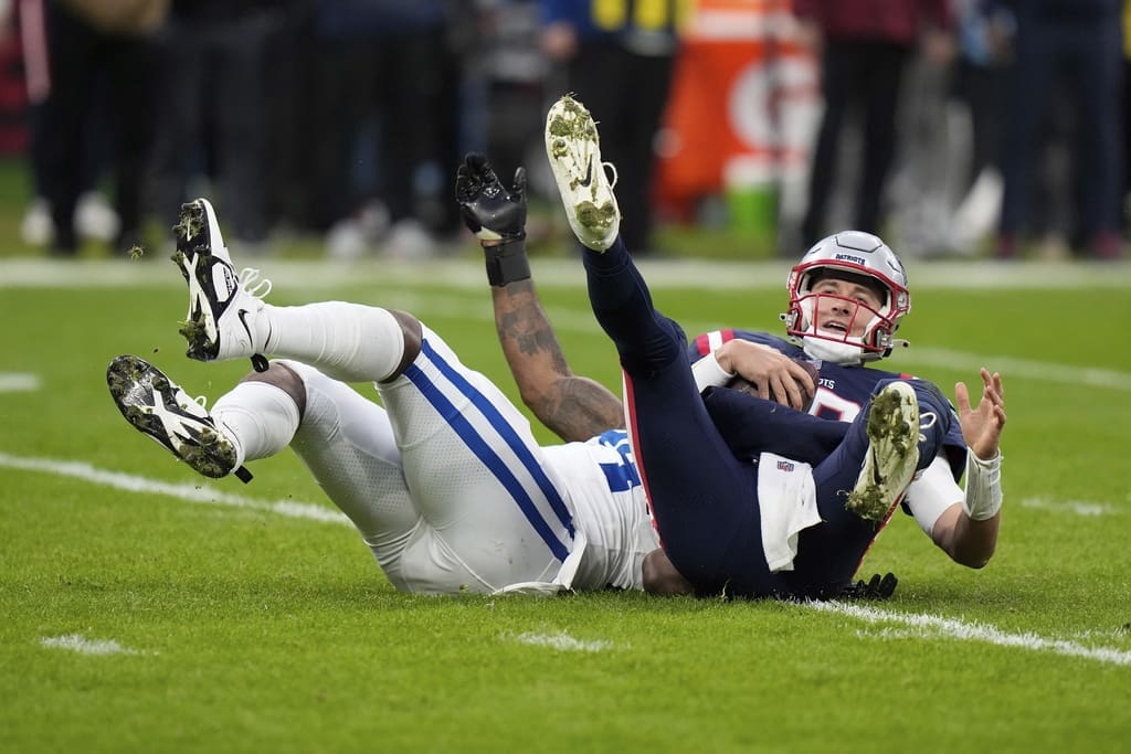 New England Patriots quarterback Mac Jones (10) is sacked by Indianapolis Colts defensive end Tyquan Lewis (94) during an NFL football game at Deutsche Bank Park Stadium in Frankfurt, Germany, Sunday, Nov. 12, 2023. (AP Photo/Doug Benc)