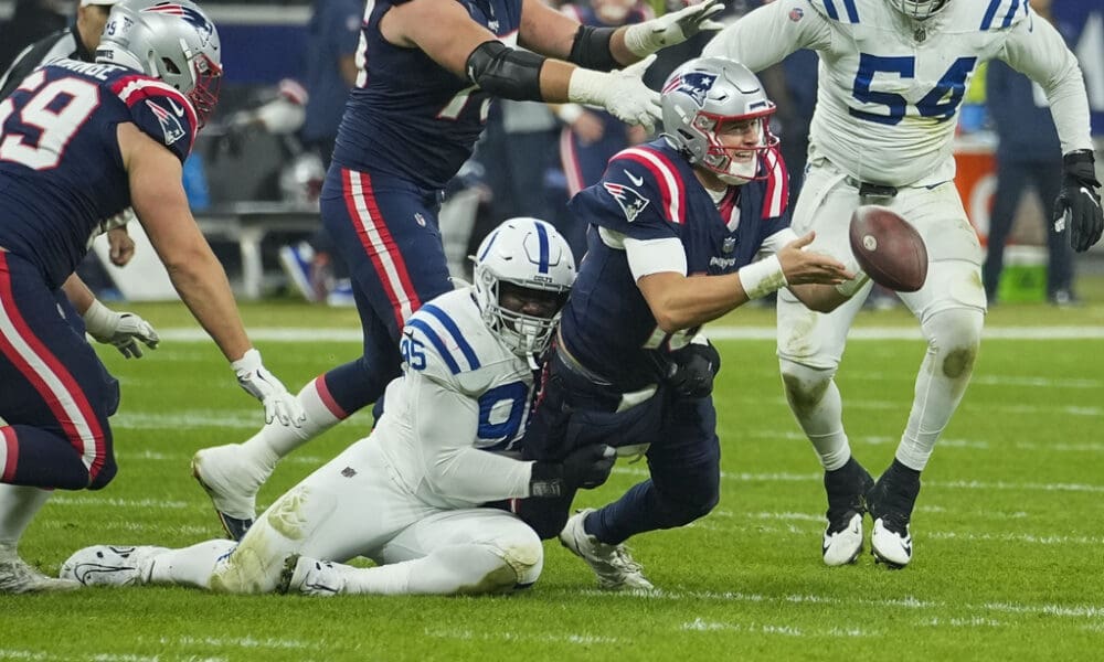 New England Patriots quarterback Mac Jones (10) pitches out as Indianapolis Colts defensive end Adetomiwa Adebawore (95) tries to tackle in the second half of an NFL football game in Frankfurt, Germany Sunday, Nov. 12, 2023. (AP Photo/Martin Meissner)