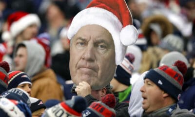 A fan holds a photo of New England Patriots head coach Bill Belichick wearing a Christmas hat during the second half of an NFL football game between the Patriots and the Buffalo Bills, Sunday, Dec. 24, 2017, in Foxborough, Mass. (AP Photo/Charles Krupa)
