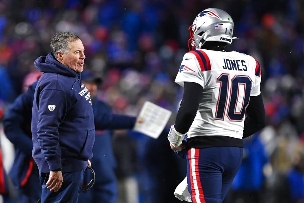 New England Patriots head coach Bill Belichick, left, talks to quarterback Mac Jones during the second half of an NFL football game against the Buffalo Bills in Orchard Park, N.Y., Monday, Dec. 6, 2021. (AP Photo/Adrian Kraus)