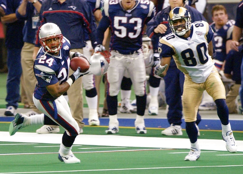 New England Patriots cornerback Ty Law (24) intercepts a pass from St. Louis Rams quarterback Kurt Warner as intended receiver Isaac Bruce (80) looks on during Super Bowl XXXVI, Sunday, Feb. 3, 2002, in New Orleans. (AP Photo/Kathy Willens)