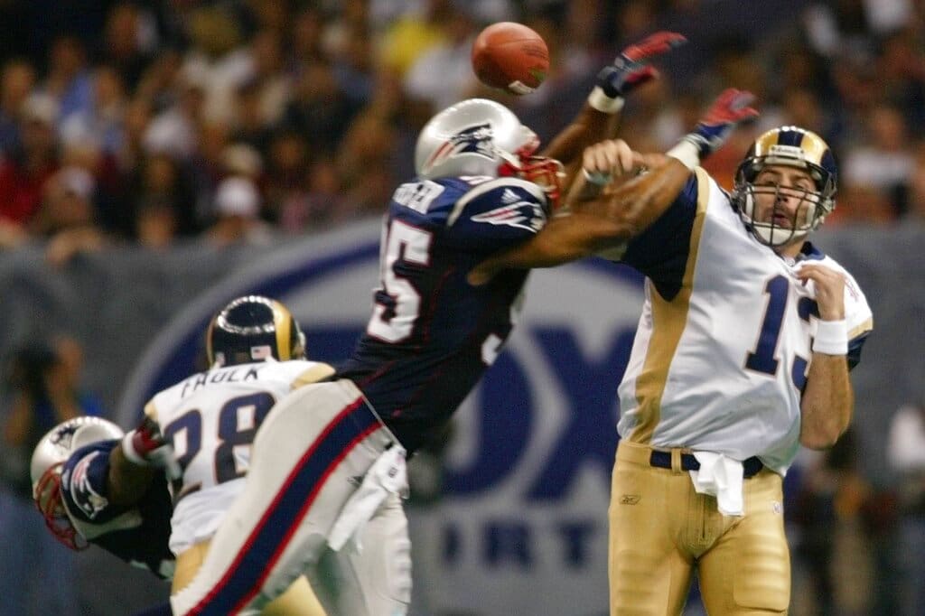 St. Louis Rams quarterback Kurt Warner, left, throws the ball as New England Patriots' Roman Phifer (95) defends during the third quarter of Super Bowl XXXVI at the Louisiana Superdome, Sunday, Feb. 3, 2002 in New Orleans. The pass was blocked and fell incomplete. Blocking on the play is Rams' Marshall Faulk (28). (AP Photo/Doug Mills)