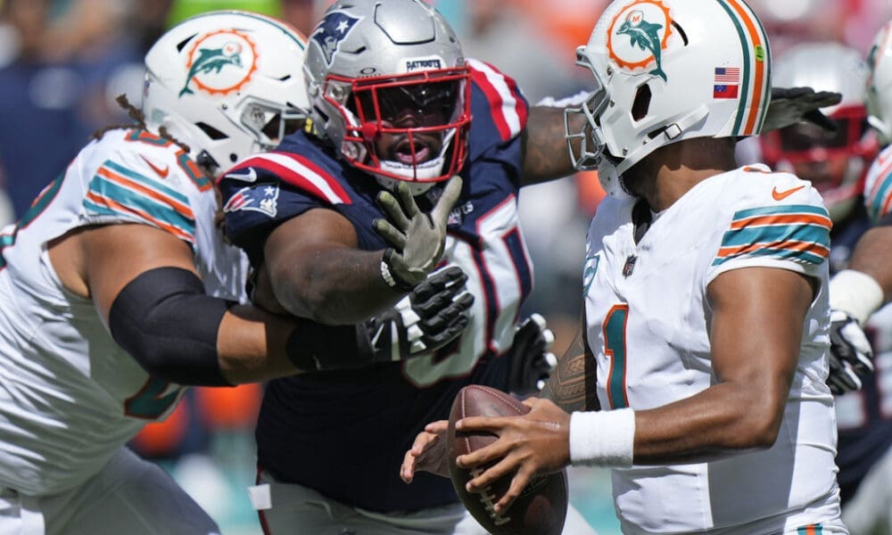 New England Patriots defensive tackle Christian Barmore, center, prepares to sack Miami Dolphins quarterback Tua Tagovailoa, right, during the first half of an NFL football game, Sunday, Oct. 29, 2023, in Miami Gardens, Fla. (AP Photo/Wilfredo Lee)