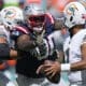 New England Patriots defensive tackle Christian Barmore, center, prepares to sack Miami Dolphins quarterback Tua Tagovailoa, right, during the first half of an NFL football game, Sunday, Oct. 29, 2023, in Miami Gardens, Fla. (AP Photo/Wilfredo Lee)